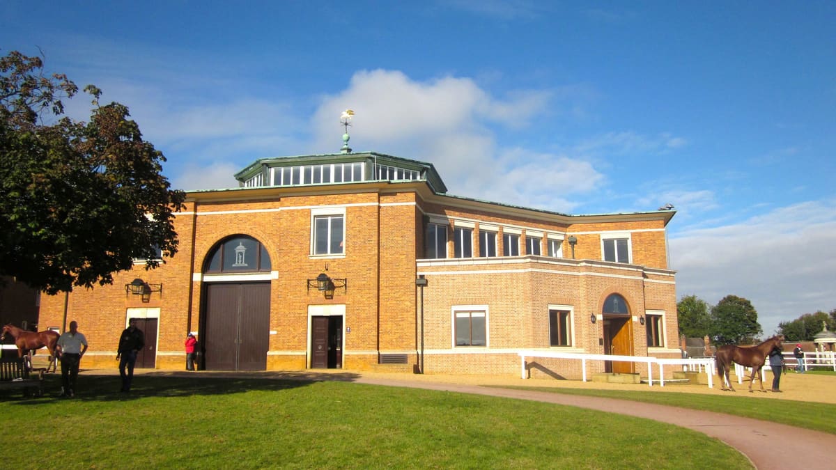 The octagonal Tattersalls sales ring building in Newmarket, with horses being led outside